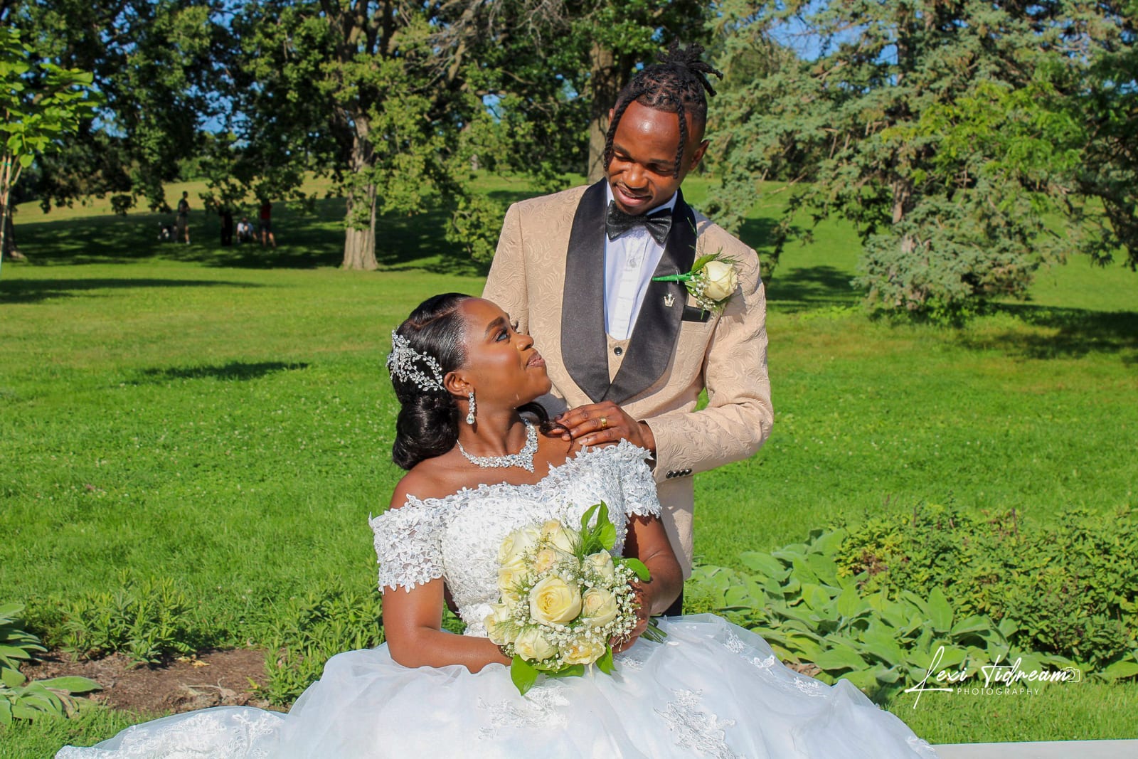 Bride and groom smiling together in a sunlit park on their wedding day