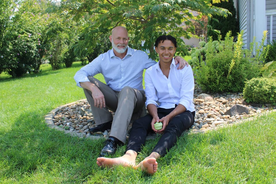 Father and son sitting together on a sunlit lawn